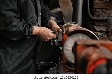 Male hands sharpening a metal tool on a grinding wheel generating sparks in a workshop. Image highlighting the artisanal process and the use of machinery for precision work. - Powered by Shutterstock