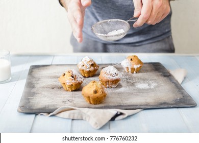 Male Hands Sprinkle Powdered Sugar Homemade Cupcakes. Man Cooking Homemade Cupcakes With Raisins And Powdered Sugar