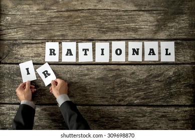 Male Hands Taking Away Letters IR From The Word Irrational Changing It Into Rational Spelled On White Cards Over Rustic Textured Wooden Planks. Conceptual Of Being Objective In Decision Making.