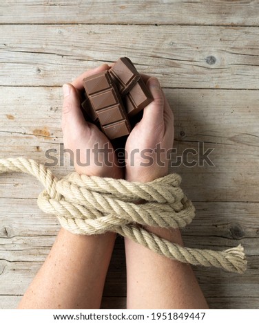 male hands are tied and hold chocolate, concept addiction, candy, sugar addiction, photo taken from above