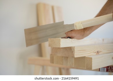 Male hands with a traditional Japanese metal carpentry saw (ryoba) with a double saw cutting a piece of wood in a carpentry