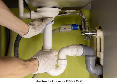 male hands twist the drain pipe under the sink in the kitchen.