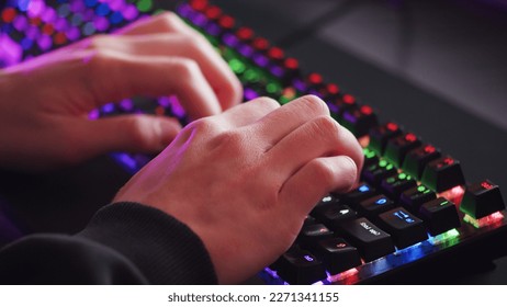 Male hands is typing on the computer keyboard, close up view. Man working on the pc computer. Human hands typing on the colourful gaming keyboard. Fingers typing on the led rgb keyboard.  - Shutterstock ID 2271341155