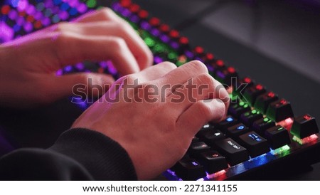 Male hands is typing on the computer keyboard, close up view. Man working on the pc computer. Human hands typing on the colourful gaming keyboard. Fingers typing on the led rgb keyboard. 