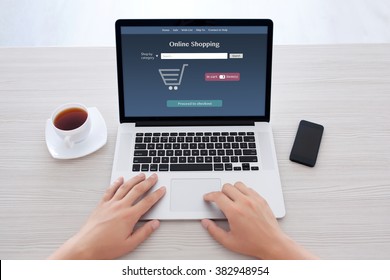 male hands typing on notebook keyboard with online shopping on the screen in the office