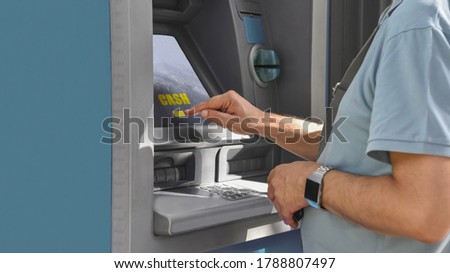Male hands using a touchscreen to withdraw money from a cash machine.