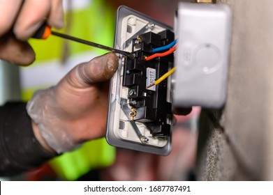 Male Hands Wiring A Uk Socket Plug On Garage Wall With Screw Driver