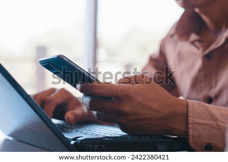 Male hands working with notebook computer and using mobile phone in office table
