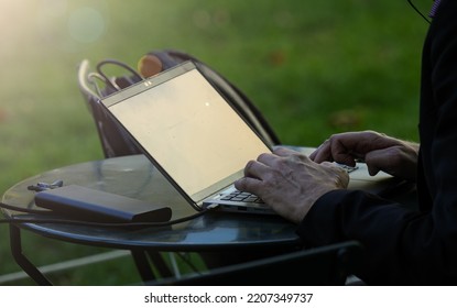 Male Hands Working On A Laptop In In The Middle Of A Green Park In The Early Morning. Remote Office All Around The World.