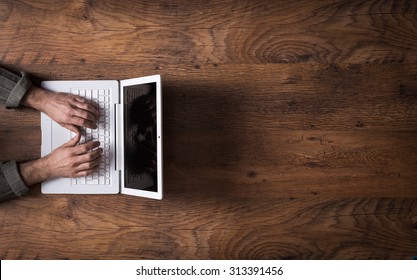 Male Hands Working On A White Laptop On A Wooden Desktop And Copy Space At Right