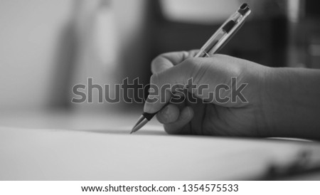 Male hands writing on a piece of paper. Writing letters or homework. Black and white photo