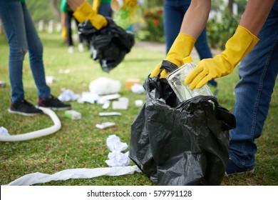 Male hands in yellow rubber gloves putting household waste into small bin bag