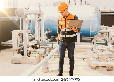 Male HAVC refrigeration system technician holds laptop recording preventive inspection refrigeration equipment Low pressure tanks contain refrigerant into the system and checked leaks ensure safety.