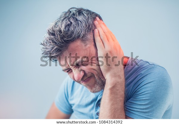 male having ear pain touching his painful head\
isolated on gray\
background