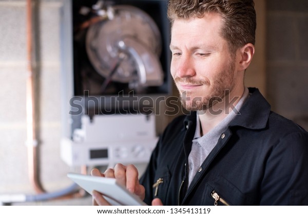 Male Heating Engineer Servicing Central Heating\
Boiler Using Digital\
Tablet