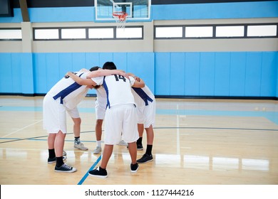 Male High School Basketball Players In Huddle Having Team Talk On Court