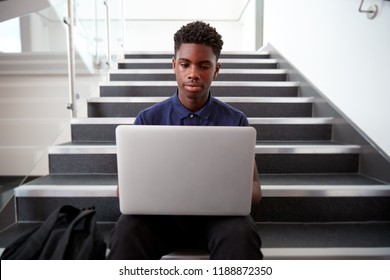 Male High School Student Sitting On Staircase And Using Laptop