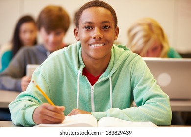 Male High School Student Studying At Desk In Classroom