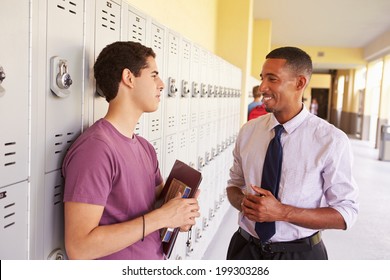 Male High School Student Talking To Teacher By Lockers