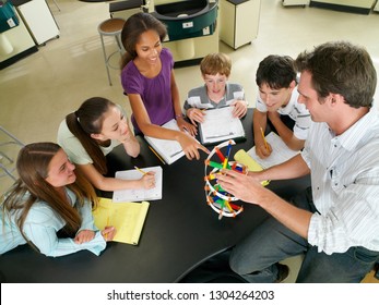 Male High School Teacher Showing Students Model In Science Class