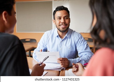 Male High School Tutor With Two Students At Desk In Seminar