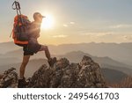 Male hiker with backpack standing on top rock mountain landscape and beautiful view sunset background.Hiker men