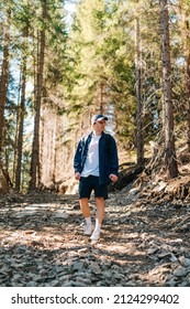 Male Hiker In Casual Clothes Walks In The Mountains On A Trail Down On A Background Of Forest On A Sunny Day