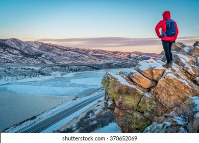 Male Hiker Contemplating Winter Sunrise Over Frozen Horsetooth Reservoir  At Rocky Mountains Foothills Near Fort Collins, Colorado