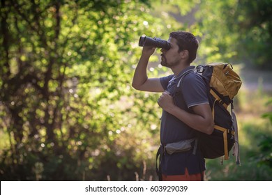 Male hiker looking through binoculars in forest - Powered by Shutterstock