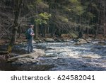Male hiker stopping at the edge of a river to enjoy the view 