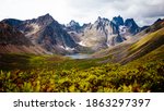 Male hiker walks in Tombstone Territorial Park, Yukon Canada. Huge stunning mountains and a lake is in the distance. Inspiring landscape. Summer and Fall hiking. Campground with tents.