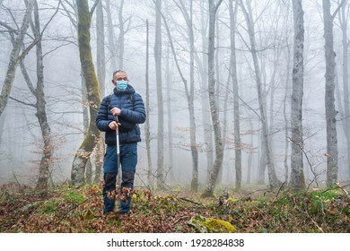 Male Hiking With Mask And Walking Sticks In A Forest.  Autumn Or Winter Landscape With Mist. Trees On The Background.