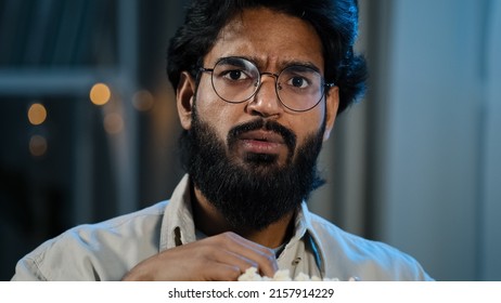 Male Home Portrait Serious Interested Attentive Arabic Hispanic Indian Bearded Man Guy In Glasses Eating Popcorn Watching TV Show Series Late Evening Night Watch Movie Online Sport Game Championship