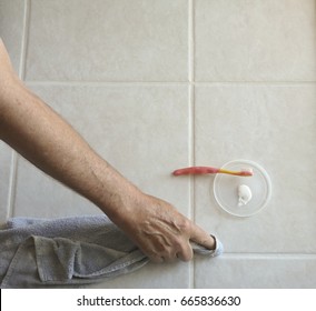 Male Homeowner Uses Toothbrush And Grout Color/sealer To Paint Tile Grout Lines In The Kitchen Of His Residence To Repel Oils And Prevent Stains.