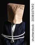 Male hostage with paper bag on dark background