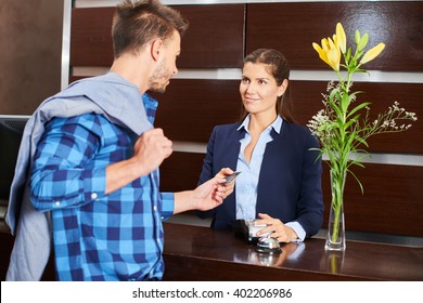 Male Hotel Guest Paying With His Credit Card At Reception