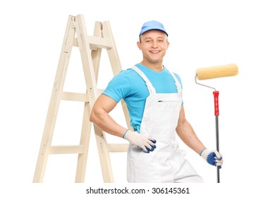 Male House Painter In A Clean White Overalls Holding A Paint Roller And Leaning On A Ladder Isolated On White Background