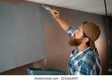 Male House Painter Painting Ceiling With Orange Paint. Repair And Home Renovation Concept