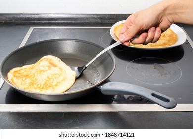 male human hand try to flip gold brown pancake by spatula while cooking breakfast for family