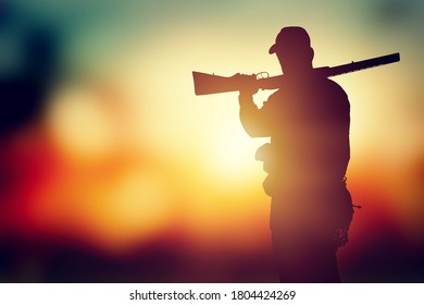 Male hunter silhouette with a gun at sunset