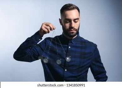 Male hypnotist with swinging pendulum on grey background - Powered by Shutterstock