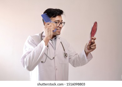 Male Indian Doctor In White Coat And Stethoscope Combing Hair By Looking At Mirror