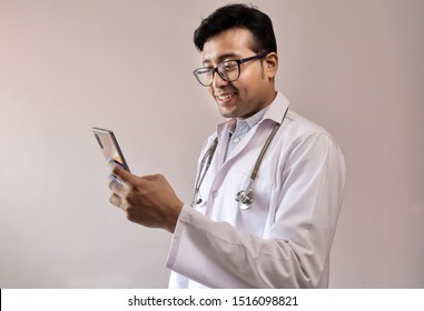 Male Indian Doctor In White Coat And Stethoscope Touching Smart Phone