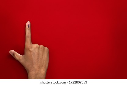 male Indian Voter Hand with voting sign or ink on red background with copy space election commission of India