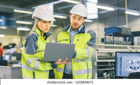 Male Industrial Worker and Female Chief Mechanical Engineer in Walk Through Manufacturing Plant while Discuss Factory's New Project and Using Laptop. Facility Has Working Machinery. - Powered by Shutterstock