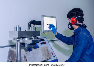 Male Industrial Worker With Protective Mask And Hearing Protectors Configures A Machine Using A Pencil And Touch Display