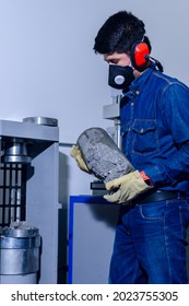 Male Industrial Worker With Protective Mask And Hearing Protectors Loading A Concrete Cylinder For Testing