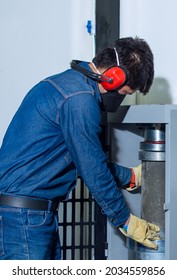 Male Industrial Worker With Protective Mask And Hearing Protectors Placing A Concrete Cylinder In A Testing Machine