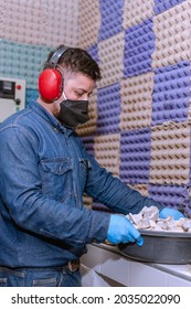 Male Industrial Worker With Protective Mask And Hearing Protectors Holding A Bowl With Stone