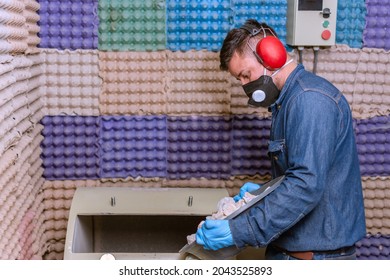 Male Industrial Worker With Protective Mask And Hearing Protectors Pouring Stones Into A Material Testing Machine